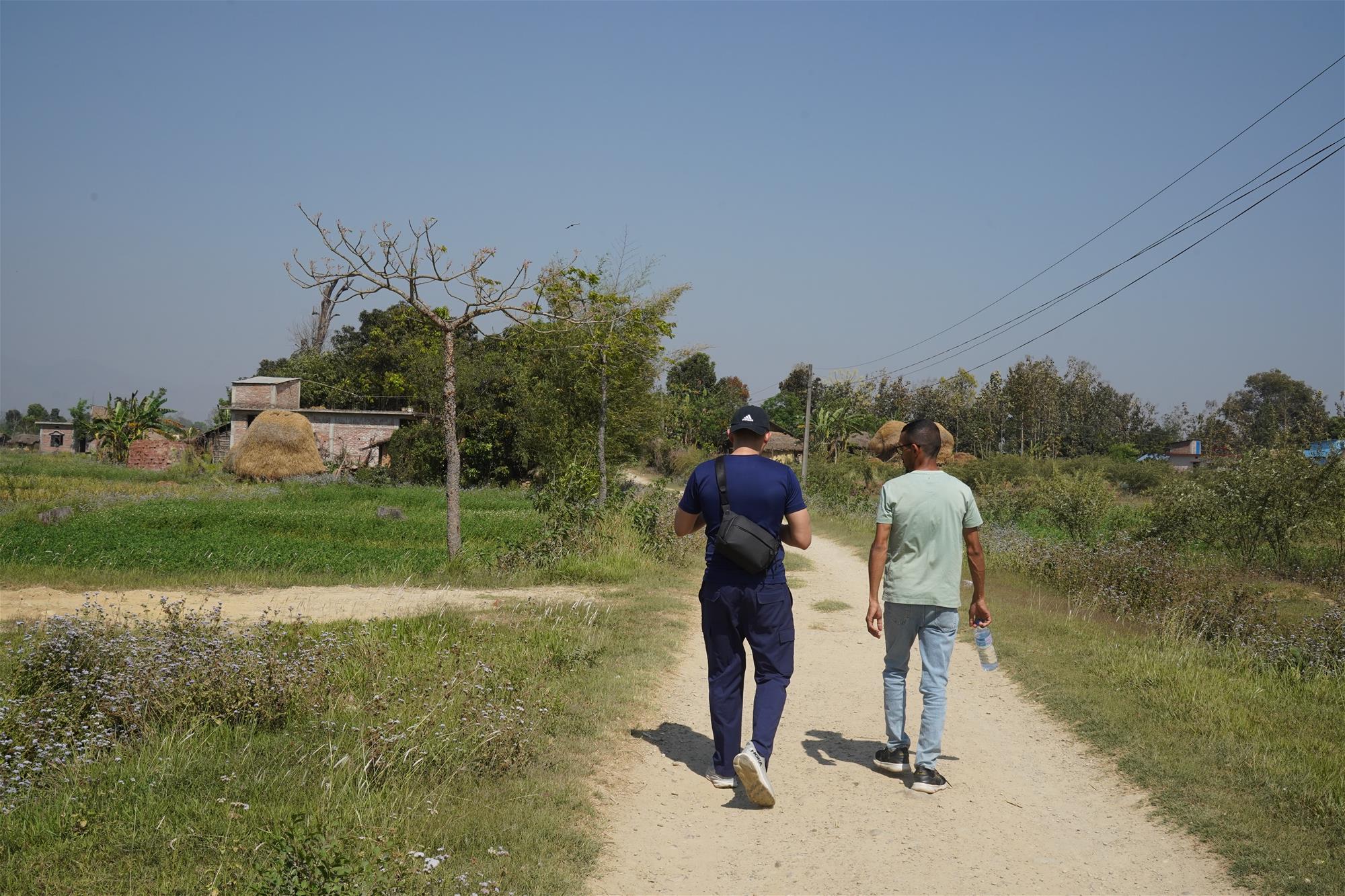 Under an unfettered sky, Yau walks along a dirt path in one of the Dang villages with a member of the community. // Credit: Project DOVE Nepal