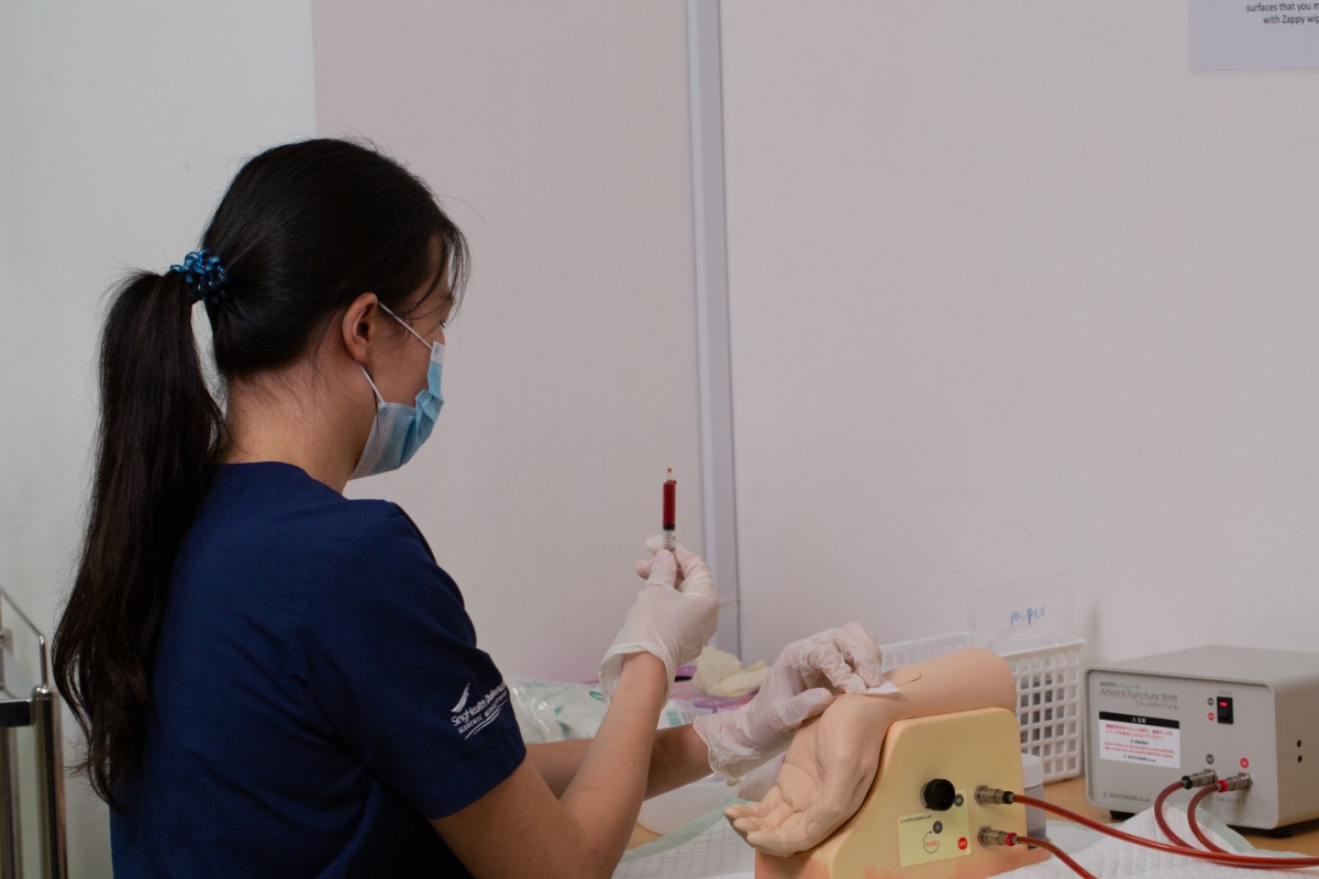 Fountain of knowledge: A student learns to draw blood from a task trainer that models an arm. // Credit: Duke-NUS Medical School